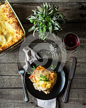 Piece of tasty hot lasagna with red wine. Small depth of field. Traditional italian lasagna. Portion. Italian food. Food on black