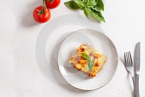 Piece of tasty hot lasagna served with a basil leaf on a gray plate. Italian cuisine, menu, recipe. Homemade meat lasagna. Copy