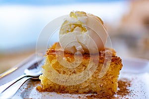 Piece of tasty vegan orange cake with vanilla ice cream served on white board