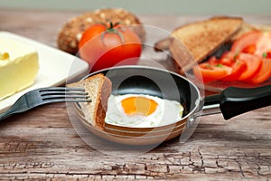 Piece of toast on a fork with fried egg in a pan photo