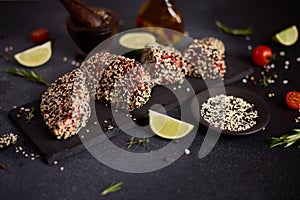 piece of tuna fillet covered with sesame seeds on a stone serving board before cooking