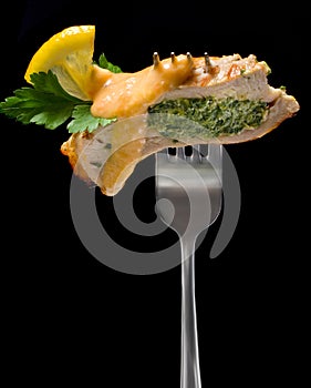 Piece of turkey stuffed with spinach decorated with lemon and parsley on a fork photo