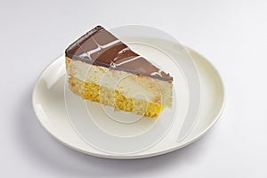 A piece of vanilla and chocolate cream cake on white background. Delicious sweet sugary dessert for tea time