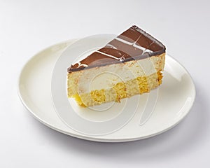 A piece of vanilla and chocolate cream cake on white background. Delicious sweet sugary dessert for tea time