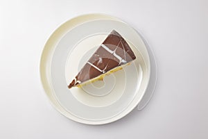 A piece of vanilla and chocolate cream cake on white background. Delicious sweet sugary dessert for tea time
