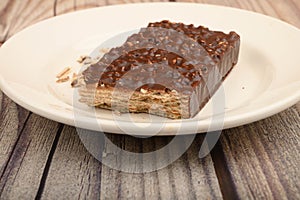 A piece of waffle cake on a white plate on a wooden background. Close up