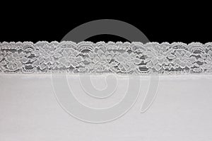 Piece of white fabric with lace isolated on black