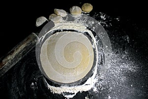 Piece of yeast dough with wheat flour on black background. Risen or proved yeast dough for bread