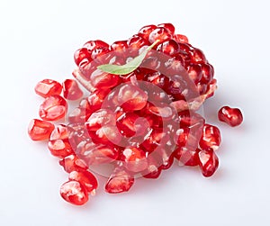 A piece of a young pomegranate with a textured peel and a mountain of beautiful young pomegranate seeds with an elegant fresh pome