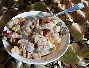 Pieces of baked meat with onions on a plate.