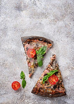 Pieces of black pizza with tomatoes and basil
