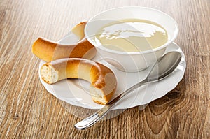 Pieces of bread rings baranka, spoon, bowl with condensed milk in plate on table photo