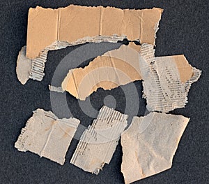 Pieces of brown cardboard paper with torn edges on textured black background