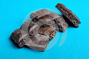 Pieces of brown porous chocolate on a blue background
