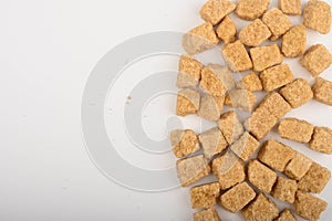 Pieces of brown sugar on white background with copyspace