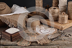 Pieces of burlap fabric, spools of twine and different sewing tools on wooden table