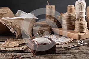 Pieces of burlap fabric, spools of twine and different sewing tools on wooden table