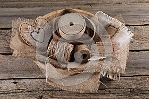 Pieces of burlap fabric and spools of twine on wooden table, above view