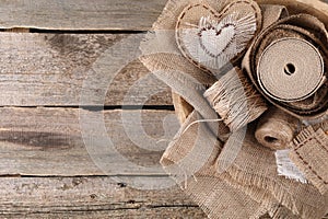 Pieces of burlap fabric and spools of twine on wooden table, top view. Space for text