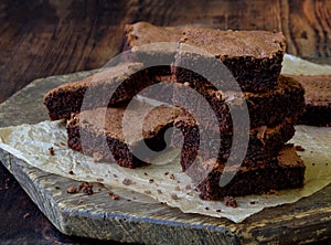 Pieces of cake chocolate brownies on wooden background.