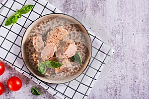 Pieces of canned tuna and basil leaves on a plate top view