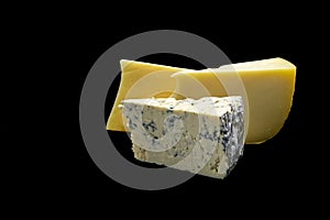 Pieces of cheese and cheese with blue mould on a black background isolate