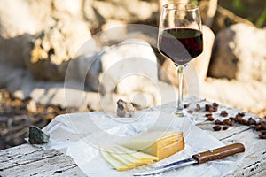 Pieces of cheese and raisins with a red wine glass on a old wood