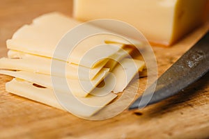 Pieces of cheese on wooden cutting board and knife