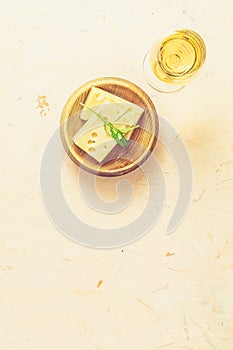 Pieces of cheese in wooden plate served with wine