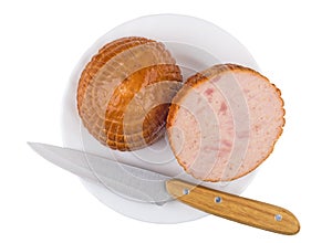 Pieces of chicken smoked sausage, knife in glass plate isolated on white. Top view