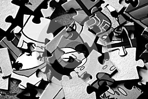 Pieces of children`s puzzles scattered on a dark background. Black and white