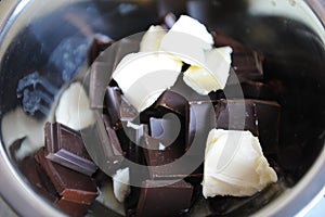 Pieces of chocolate and butter melt in a steel bowl. The process of making candy or dessert