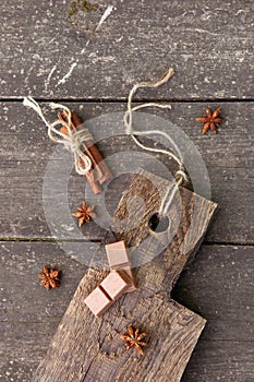 Pieces of chocolate, cinnamon sticks and star anise on a wooden board, photo rusticstyle