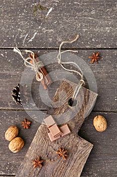 Pieces of chocolate, cinnamon sticks and star anise on a wooden board, photo rusticstyle