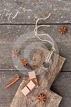Pieces of chocolate, cinnamon sticks and star anise on a wooden board, photo rusticstyle
