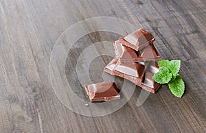 Pieces of chocolate with mint lying on a wooden