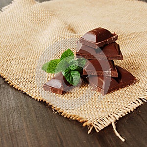 Pieces of chocolate with mint lying on a wooden