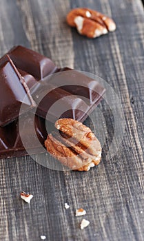 Pieces of chocolate with walnuts lying on a wooden