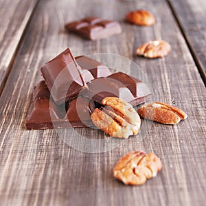 Pieces of chocolate with walnuts lying on a wooden