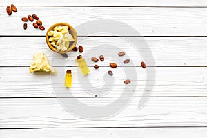 Pieces of cocoa butter in bowl for homemade cosmetics. White wooden background top view space for text