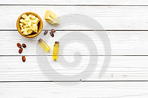 Pieces of cocoa butter in bowl for homemade cosmetics. White wooden background top view space for text