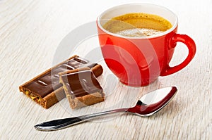 Pieces of cookie with chocolate and caramel, cup with espresso, spoon on table