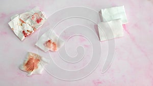 Pieces of cotton pads and tissue paper with red stain from wiping off make-up, and also clean cotton pads.