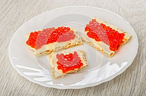Pieces of crispbread with butter and imitation caviar in plate on wooden table