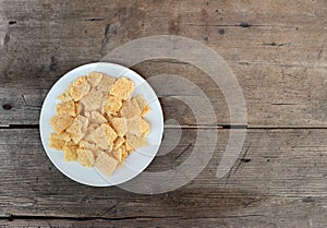 Pieces of crunchy dry Frico in a white plate on weathered wooden table. It is a traditional friulian snack.