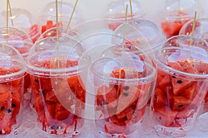 Pieces of cut up watermelon in a clear plastic cup on a hot day