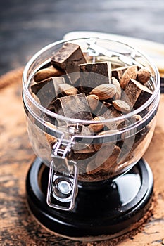 Pieces of dark bitter chocolate with cocoa and nuts almonds on wooden background. Concept of confectionery ingredients