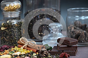 pieces of dark chocolate near jars of teas and aromatic seasoning.