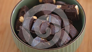 Pieces of dark chocolate with nuts in bowl.