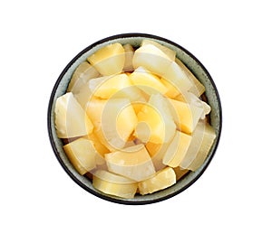 Pieces of delicious canned pineapple in bowl on background, top view